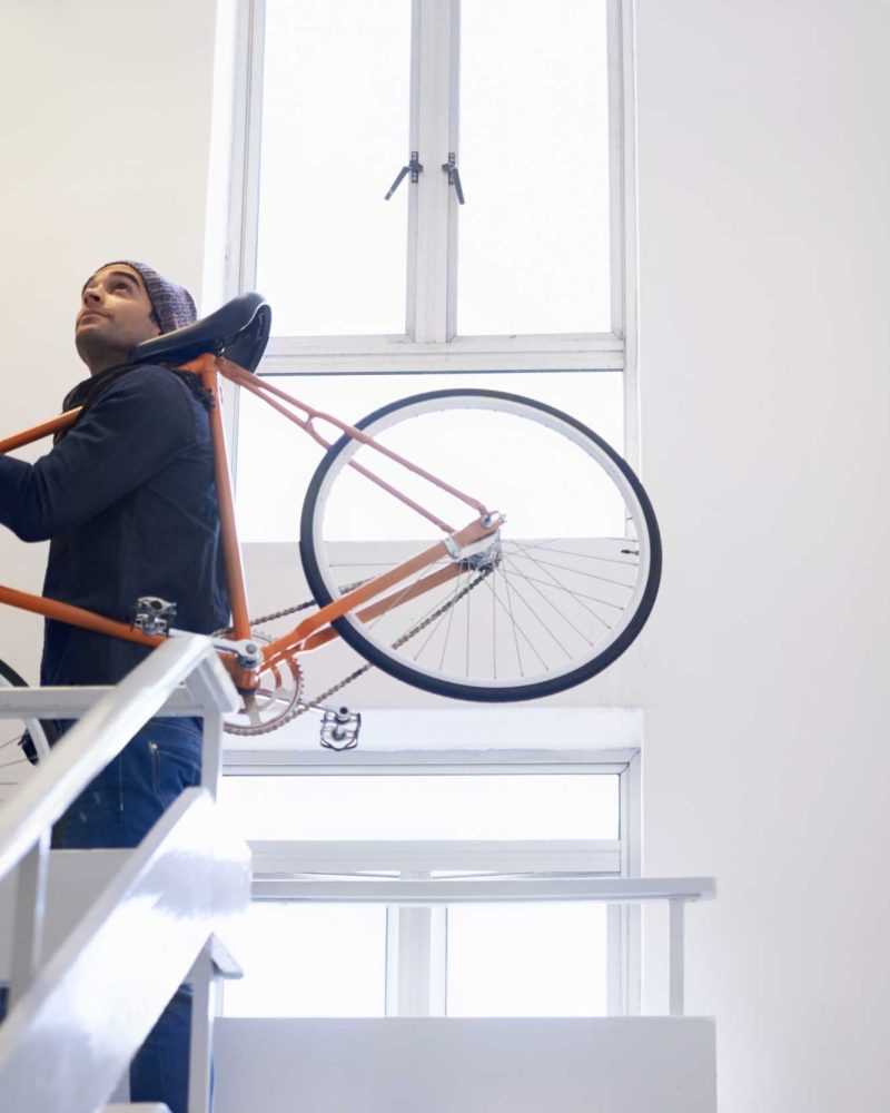 Mann trägt Fahrrad ducht das Treppenhaus